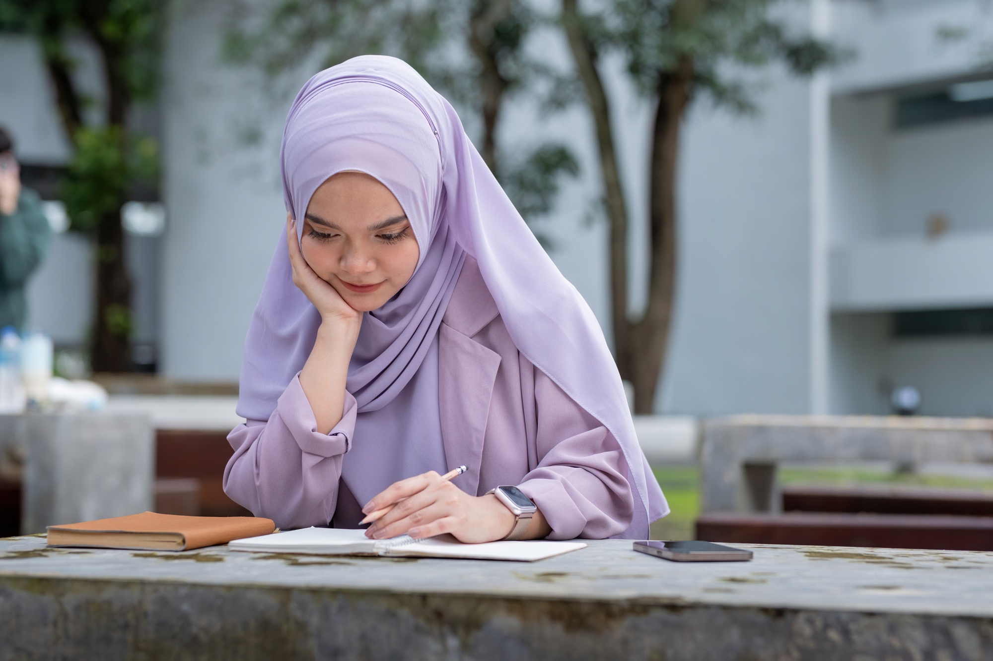 Beautiful Muslim college student girl taking note at university